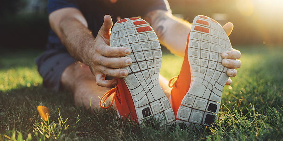 men stretching holding on to sneakers